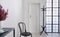 Black chair in white corridor of elegant apartment, real photo with copy space