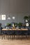 Black chairs at wooden table in grey dining room interior with l