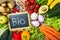 Black Chalk Board with Bio Texts with Assorted Organic Veggies on Sides on Top of Wooden Table