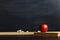 Black chalk board over wooden table with a book and an apple, blank for text or background for a school theme