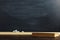 Black chalk board over wooden table with book, blank for text or background for school theme