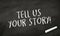 Black chalkboard with message Tell us your story
