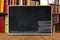 Black chalkboard with stack books chalk style on wooden table wi