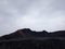 Black charcoal mountain silhouette against the cloudy sky