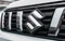 Black and chrome trim around Suzuki logo on front of a silver car