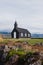 Black church in the meadow and field in Iceland. Icelandic scenic travel destination of religion.