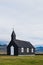 Black church in the meadow and field in Iceland. Icelandic scenic travel destination of religion.