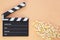 Black clapperboard and popcorn with free space for text isolated on color background