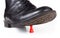 Black classy boot stomping and crushing a small red pawn game piece under sole. Big vs small, power, danger and helplessness