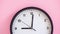 Black clock on pink background close up