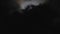 Black clouds passing in front of the moon in the night sky. Outdoor at nighttime.