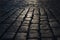 Black cobbled stone road background with reflection of light seen on the road. Black or dark grey stone pavement texture.