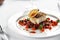 Black cod fillet on a vegetable stew, festive serving on a white grater on a table with white tablecloths.
