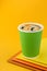 Black Coffee Americano in green paper cup on colorful yellow background. Mockup. Black coffee take away.