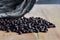 Black coffee beans laid on a wooden floor, behind a beautiful patterned log.