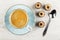 Black coffee in cup on saucer, chocolate candies, spoon on wooden table. Top view