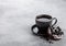 Black coffee cup with saucer and doughnut with black cookies on stone kitchen table background. Space for text. Breakfast snack