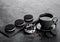 Black coffee cup with saucer and doughnut with black sandwich cookies on black stone kitchen table background. Space for text. Bre