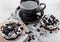 Black coffee cup with saucer and doughnuts with black cookies on stone kitchen table background. Breakfast snack. Doughnut on roun