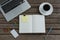 Black coffee, laptop, organizer and stationery on wooden plank