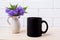 Black coffee mug mockup with blue Ageratum in pitcher