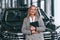 Black colored document in hands. Woman in formal clothes is in the car dealership