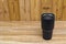 Black colour stainless steel tumbler or cold and hot storage cup on wood