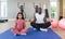 à¸ºBlack Cornrow Braids girl in sportswear meditating with her father on yoga mat before exercise. Two yoga ball are placed next