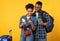 Black Couple Booking Travel Tickets Using Smartphone Over Yellow Background