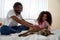 Black couple caressing their dog on bed at home