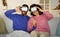 black couple engrossed in online simulation via VR headsets indoors