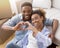 Black Couple Gesturing Heart Shape Sitting Among Moving Boxes Indoor