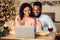 Black couple having videocall using laptop drinking wine waving hands