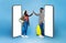 Black couple with luggage high fiving each other on blue