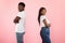 Black couple standing back to back, pink studio wall