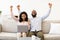 Black couple using laptop celebrating success with clenched fists