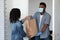 Black courier guy in medical mask delivering grocery order to woman