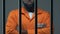 Black criminal with hands crossed standing in prison cell, waiting for judgment