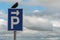 Black crow sitting on a blue and white parking sign with direction to the right arrow,