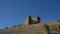 Black crows fly in the sky over the fortress on a rock