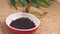 Black Cumin drops in a container with oil in a jar on table.