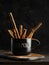 Black cup with cinnamon sticks on a dark background. Close-up. There are no people in the photo. Aromatic spices, seasonings,