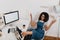 Black curly girl is scattering the documents while sitting on chair with legs on the table. Young woman in trendy