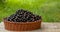 Black currant basket on wooden table on the green background