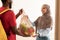 Black deliveryman giving net mesh bag with groceries