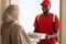 Black deliveryman holding and giving pizza boxes to muslim customer