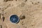 Black directional compass on golden sand. Focus on compass