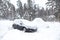 Black dirty car under the snow in forest. Heavy snowfall. Frozen car in snowdrift. winter problems to start engine