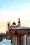 Black domes with crosses on top of orthodox church of red and white brick in winter evening landscape of residential