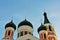 Black domes with crosses on top of painted in red and white orthodox church, The Holy Treasury Saints Temple, bright blue sky